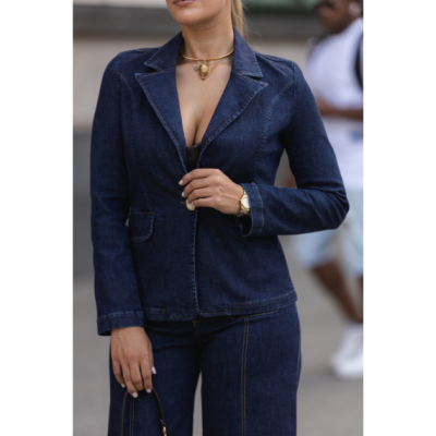 Conjunto de blazer e calças de ganga azul escuro com costuras castanhas em cenário urbano.