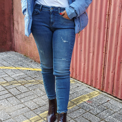 Calças de ganga azuis com detalhes desfiados e botas castanhas em ambiente urbano