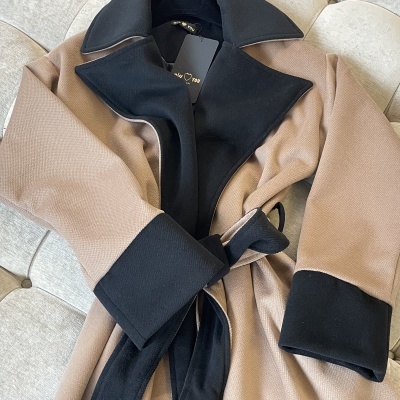 Casaco feminino bege e preto com detalhes contrastantes e cinto