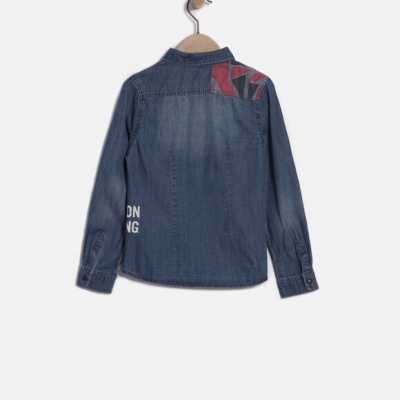 Camisa de ganga azul escuro com padrão vermelho nas costas pendurada num cabide.