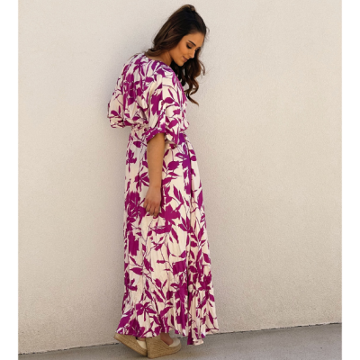 Vestido comprido branco com padrão floral roxo, sandálias de cunha bege, parede branca