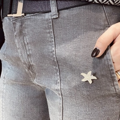 Calças de ganga cinzentas com broche em forma de estrela do mar e cinto preto