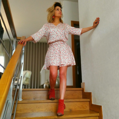 Mulher descendo escadas de vestido branco com corações vermelhos e botas vermelhas.