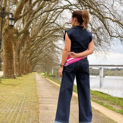 Mulher de costas com roupa de ganga escura junto a rio e árvores