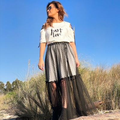 Mulher com t-shirt branca 'just love' e saia preta tule ao ar livre
