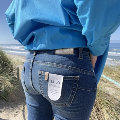 Jeans azuis escuros com etiquetas LIU·JO BOTTOM UP junto a uma praia