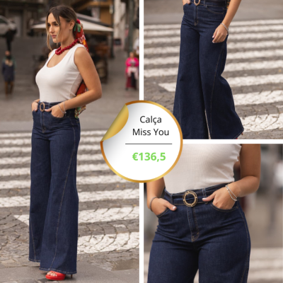 Calça de ganga flare escura com cinto de fivela dourada em mulher com blusa branca, pulseiras e colar vermelho