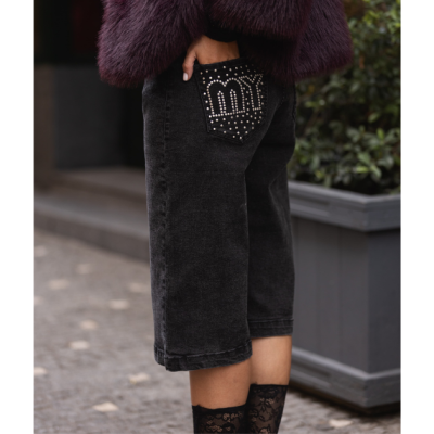 Calças pretas de ganga com bolso traseiro decorado com tachas brancas formando a palavra 'my'