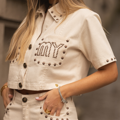 Conjunto de roupa feminino beige com tachas metálicas e escrita em tachas