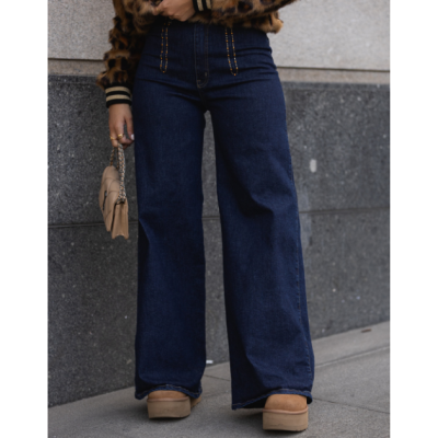 Calças de ganga largas azul escuro com detalhes laranja nas costuras frontais, usadas com casaco animal print e bolsa bege