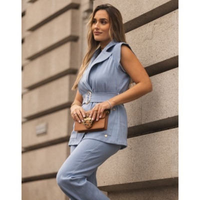 Conjunto feminino azul claro com colete e calças e carteira castanha.