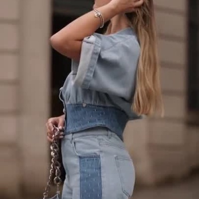 Mulher a usar conjunto de ganga azul claro com faixas laterais escuras e mala azul clara com corrente prateada