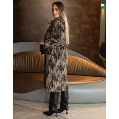 Casaco comprido feminino bege e preto com botas pretas em ambiente interior