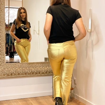 Calças douradas brilhantes e t-shirt preta refletidas em espelho com moldura decorativa