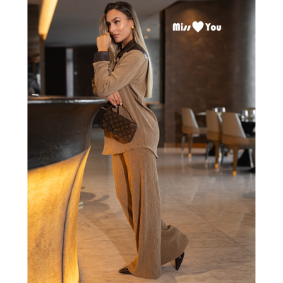 Mulher de roupa castanha com mala castanha num interior moderno com texto 'Miss ❤ You' na parede