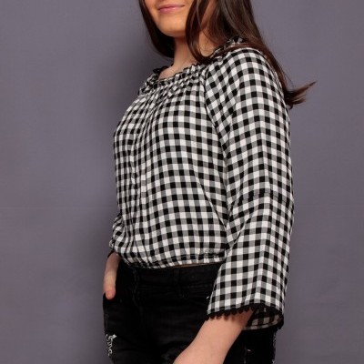 Rapaz com camisa xadrez preto e branco e calções pretos contra fundo cinza