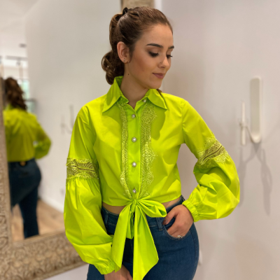 Blusa feminina amarela neon com renda e botões, combinada com calças jeans azuis