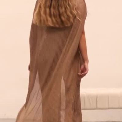 Modelo feminina a desfilar roupa castanha de tecido riscado com calças largas e top comprido