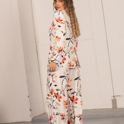 Fato feminino bege com padrão floral em tons de laranja, preto e cinza, usado por modelo com cabelo comprido ondulado.
