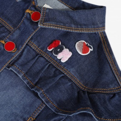 Pormenor de roupa de ganga azul com botões vermelhos e patches bordados coloridos