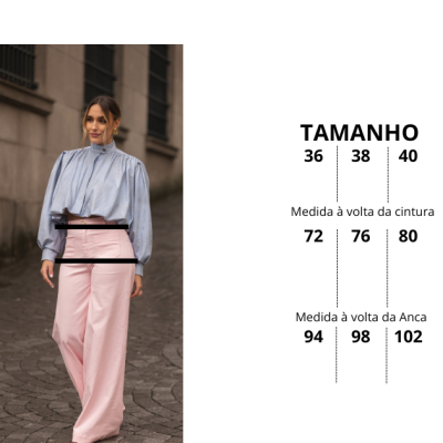 Mulher com blusa azul clara de mangas longas e calças largas cor-de-rosa claro num cenário urbano