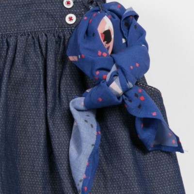 Vestido azul escuro com botões brancos e lenço azul com padrões geométricos