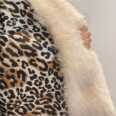 Tecido animal print castanho e preto com faixa felpuda creme, mão segurando a faixa.