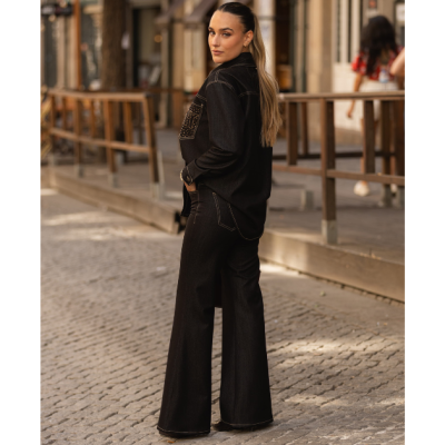 Conjunto feminino preto em tecido denim com detalhes brilhantes, apresentado em ambiente urbano