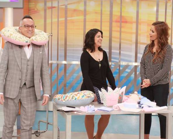 Pessoa com almofada de pescoço floral e mesa com produtos similares e acessórios