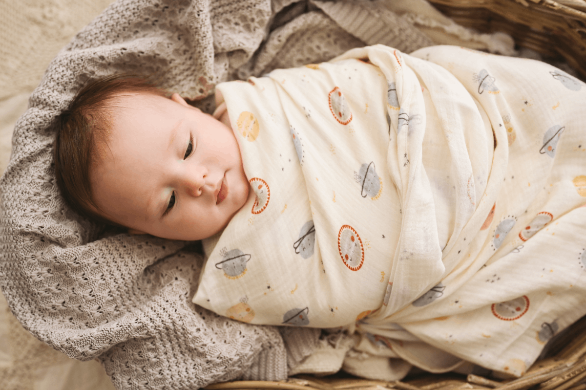Fralda Swaddle bebé embrulhado em cobertor com padrões de planetas na cesta