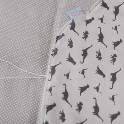 Tecidos cinzento com pontos brancos e branco com padrão de dinossauros pretos, etiqueta azul 'Luce soñare'