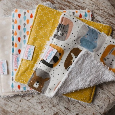 Seis panos de fralda para bebé com padrões coloridos e textura felpuda sobre madeira