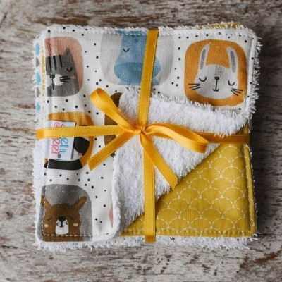 Fralda de tecido estampada e felpuda com laço amarelo num fundo de madeira desgastada