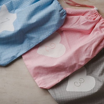 Três sacos de pano coloridos com números e formas, sobre superfície clara