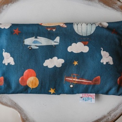 Almofada azul com aviões, elefantes e balões coloridos numa bandeja de madeira clara