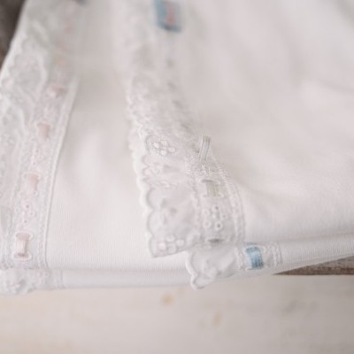 Toalhas brancas com renda e laços coloridos numa tigela de cerâmica