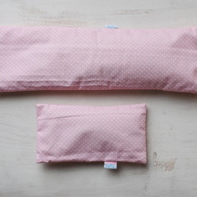 Dois sacos almofada cor-de-rosa com pontos brancos sobre madeira clara