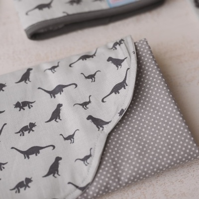 Manta cinzenta com padrão de dinossauros e pontos brancos