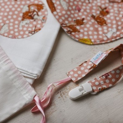 Babete e prendedor de chupeta rosa com bolinhas brancas e desenhos de animais castanhos