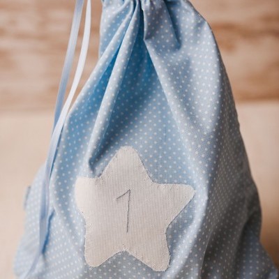 Saco de pano azul claro com pontos brancos e estrela branca com número 1