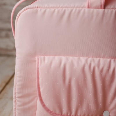 Mala rosa clara com bolso frontal de pontos brancos e botão de pressão