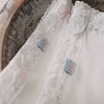 Tecidos brancos com bordados e etiquetas MISTERPIECE numa tigela de madeira