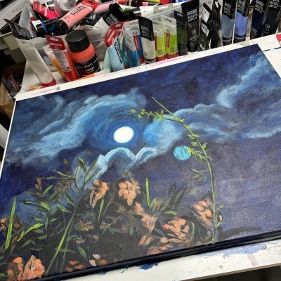 Tela pintada com paisagem noturna e tintas acrílicas ao fundo