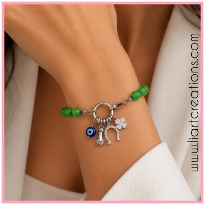 Pulseira com contas verdes e pingentes prateados no pulso