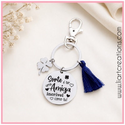 Porta-chaves metálico com pendente gravado e tassel azul sobre tecido claro