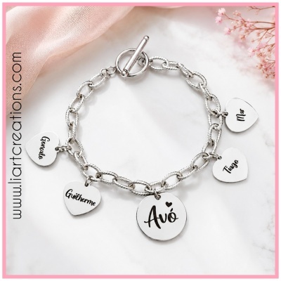 Pulseira prateada com pendentes em forma de coração e circular com nomes gravados