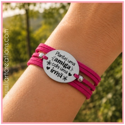 Pulseira rosa com placa metálica com frase gravada usada no pulso num fundo natural