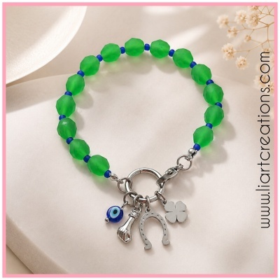 Pulseira verde com detalhes azuis e pendentes metálicos em fundo branco com flores secas