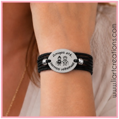 Pulseira preta com placa prateada e texto Amigas até... sermos velhinhas