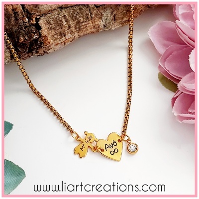 Colar dourado com pendentes e corrente em fundo branco com flor rosa e casca de árvore
